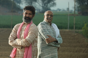 Happy Indian farmers standing in the mustard field and enjoying the benefits from the flourished rural mustard crop