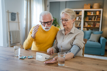 senior couple at home woman check blood pressure husband sit beside