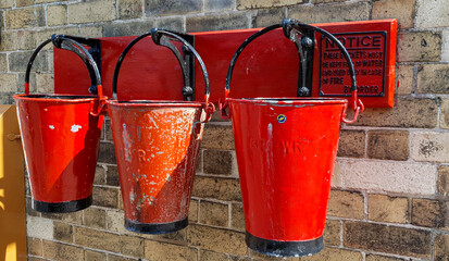 Naklejka premium Three old fashioned red metal fire buckets hanging in a row