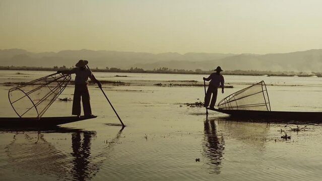 Myanmar travel attraction landmark - Traditional Burmese fishermen with fishing net at Inle lake in Myanmar famous for their distinctive one legged rowing style, 4k