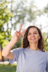 positive glad friendly cute lady toothy smile show v-sign urban city outside