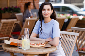 Woman eating tasty pizza outdoor in street cafe. Fast food takeaway in sunny day
