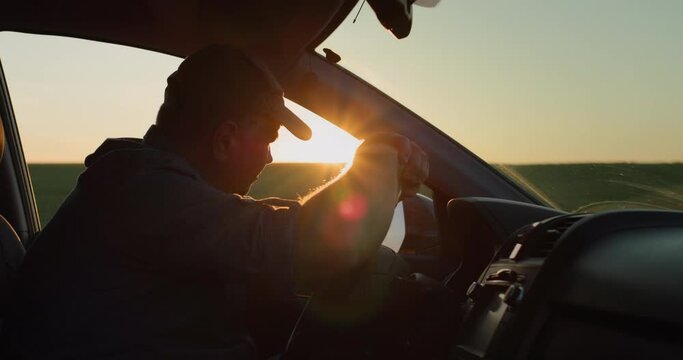 Depressed man sitting behind the wheel of a car