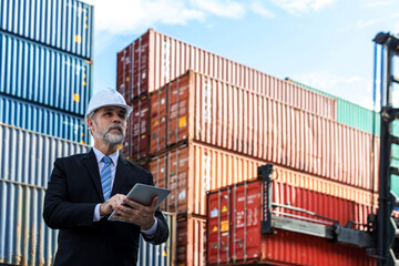 Business man holding a tablet  and checking the list of export and import orders through the port...
