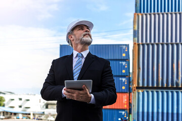 Business man holding a tablet  and checking the list of export and import orders through the port...