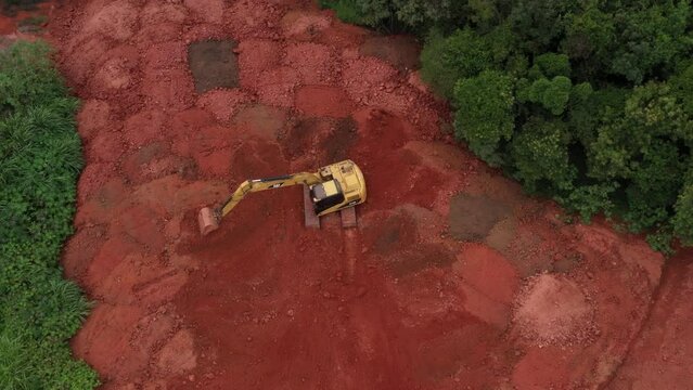 Escavadeira movimentando terra vermelha