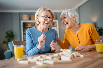 two senior women friends or sisters play leisure board game at home - obrazy, fototapety, plakaty