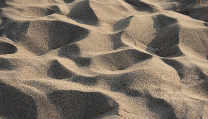 Sand on the beach in close-up and perspective. Beach holiday. The uneven surface of trampled sand hot from the sun.