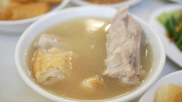 using chopsticks to grab pork rib from a bowl of bak kut teh with hot soup in lunch dinner meal time. Hot soup in asian singapore malaysia style.