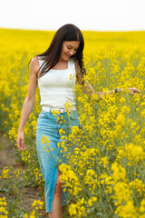 Naklejka na ściany i meble Happy beautiful woman walking on the field with yellow flowers