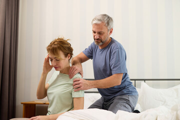 Mature man giving a shoulder massage to his wife at home