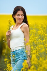 Naklejka na ściany i meble Happy beautiful woman walking on the field with yellow flowers