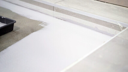 Floor waterproofing, white. Working waterproofing around the wall, floor. Painting the floor with white paint in the garage. The floor is painted white.