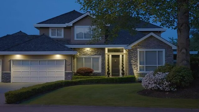 Establishing shot of two story stucco luxury house with garage door, big tree and nice landscape at night in Vancouver, Canada, North America. Night time on Apr 2023. ProRes 422 HQ.