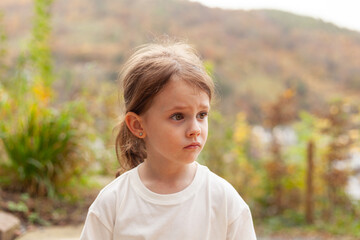 Portrait of a sad little girl in the park. Selective focus.