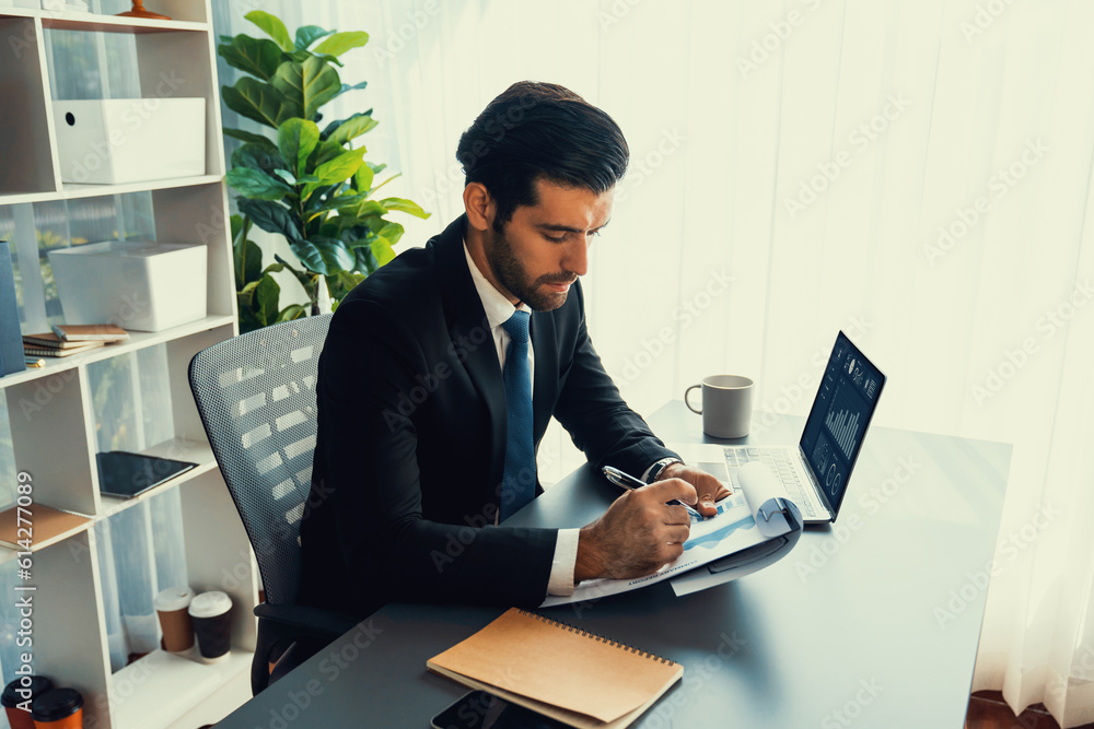 Poster modern professional businessman at modern office desk using laptop to work and write notes. diligent