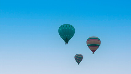 Fototapeta premium Cappadocia Turkey. Hot air balloons flying over fairy chimneys at sunrise in Cappadocia. Travel to Turkey. Touristic landmarks of Turkiye. Selective focus included.