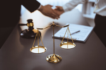 Focus gavel and justice scale on blur background of lawyer colleagues handshake after successful...