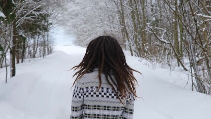 Young pretty Caucasian woman with dreadlocks dancing in snowy winter forest road. Christmas spirit. Girl with red fluffy Santa hat and gray sweater outside enjoying vacation. 4k slow motion Footage. - Powered by Adobe