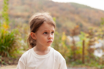 Portrait of a little girl in a white t-shirt on the nature