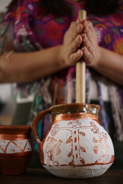 Guatemalan mayan woman making hot chocolate with molinillo blending stick