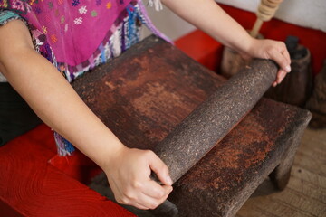 Guatemalan mayan woman making chocolate with traditional grinding stone