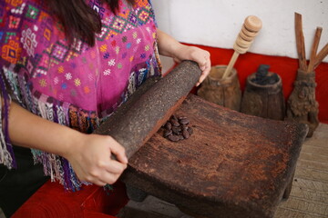 Guatemalan mayan woman making chocolate with traditional grinding stone