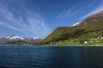 Fjord, houses near the sea in Northern Norway, sea, wooded mountains, snowy mountains