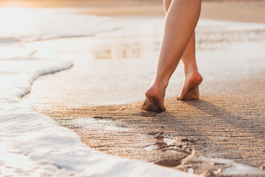 Beach Travel - Woman Walking On Sand Beach Leaving Footprints In The Sand. Closeup Detail Of Female Feet And Golden Sand On Tenerife Beach..