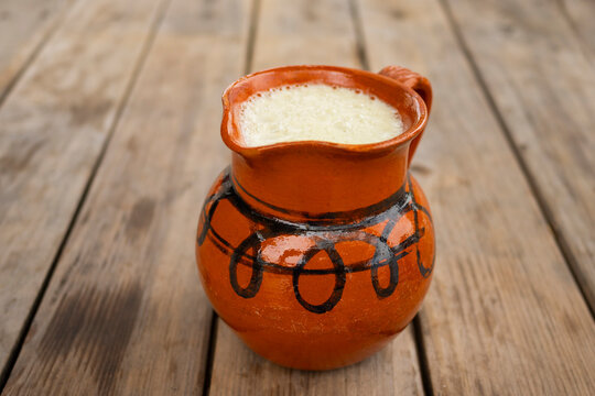close up pulque mexican craft drink in a clay jar on a wooden table selective focus