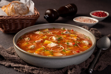 Traditional romanian soup with pork meat, vegetables and noodles, named ciorba de porc. Dark background.