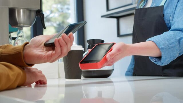 Close-up: a customer makes a purchase in a coffee shop, pays with a QR code. Scans the QR code with a smartphone in the bank's application. New technologies in digital finance. Electronic payment