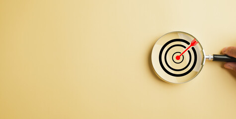 Magnifier glass centers on a target board, symbolizing the drive to achieve business objectives....