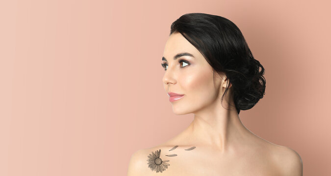 Young woman with beautiful flower tattoo on pale peach background, space for text. Banner design
