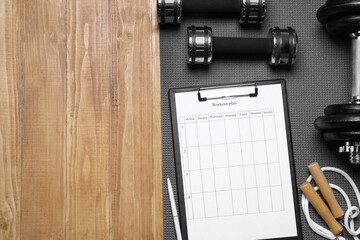 Personal training. Clipboard with workout plan and sports equipment on wooden table, flat lay....