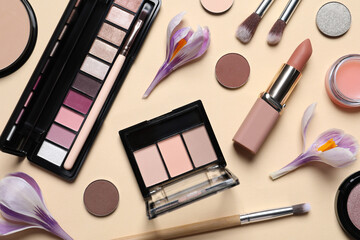 Flat lay composition with different makeup products and beautiful flowers on beige background