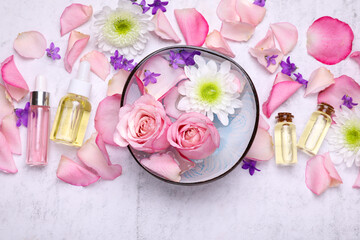 Flat lay composition with bowl of water and beautiful flowers on light table. Spa treatment