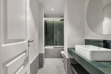 a modern design bathroom with a bathtub with a tempered glass screen, green tiles