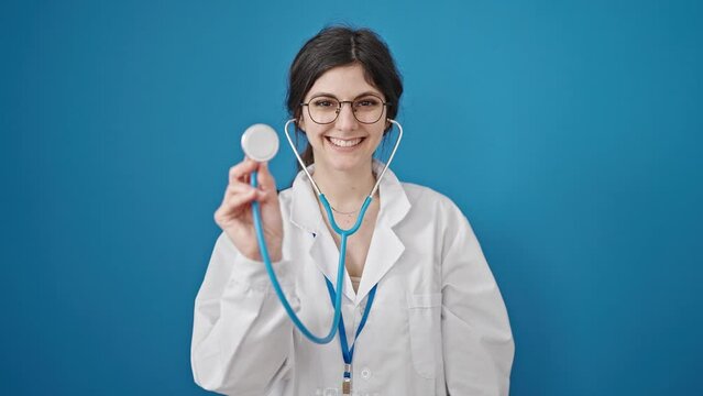 Young beautiful hispanic woman doctor smiling confident holding stethoscope over isolated blue background
