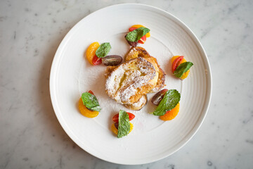 French toast with maple syrap, rasp berry sauce and fruits on a white plate.