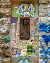 looking through a doorway into an abandoned stone building with graffitti on the walls