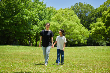 Naklejka na ściany i meble 夏の公園で楽しく散歩している親子の姿