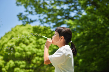 夏の公園で楽しくしゃぼん玉を遊んでいる子供