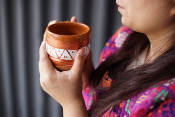 Closeup of a woman drinking hot chocolate from a rustic clay cup in Guatemala
