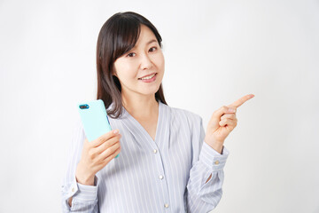 スマートフォンを持って右側を指差すミドルエイジ女性　白背景