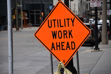 Utility Work Ahead orange construction street sign in urban city