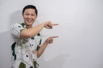 Young asian man wearing vintage shirt gesturing something, pointing, showing