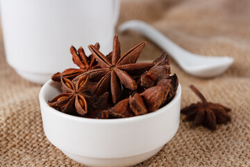 star anise in a white ceramic cup, on burlap