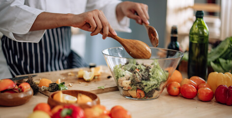 The professional master chef prepares a bowl of various types of fruit and vegetable salad with great passion and enthusiasm. Expertly mix all the ingredients and materials with care and precision.