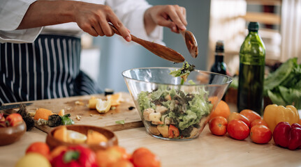 The professional master chef prepares a bowl of various types of fruit and vegetable salad with great passion and enthusiasm. Expertly mix all the ingredients and materials with care and precision.